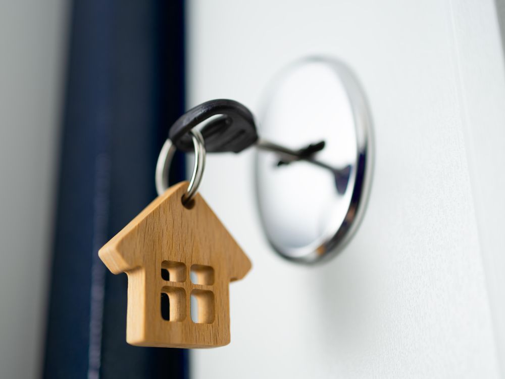 Chave na fechadura com pingente de casa, representando como funciona o aluguel sem fiador e a liberação do imóvel ao inquilino.