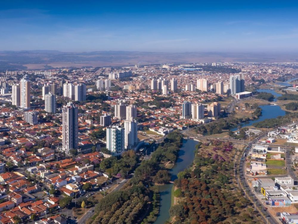 Panorama aéreo de Indaiatuba com rio, bairros residenciais e edifícios, ilustrando Curiosidades sobre Indaiatuba e seu crescimento organizado.