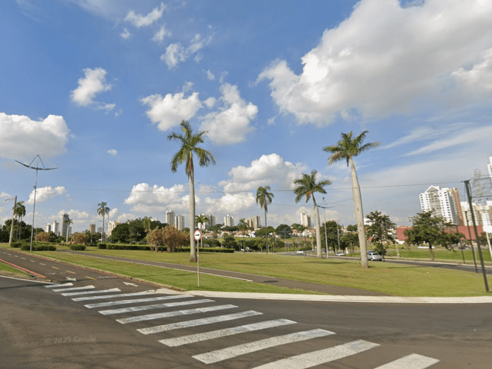 Área ampla e arborizada com gramado, ciclovia, palmeiras e edifícios ao fundo, destacando o ambiente urbano de Indaiatuba.