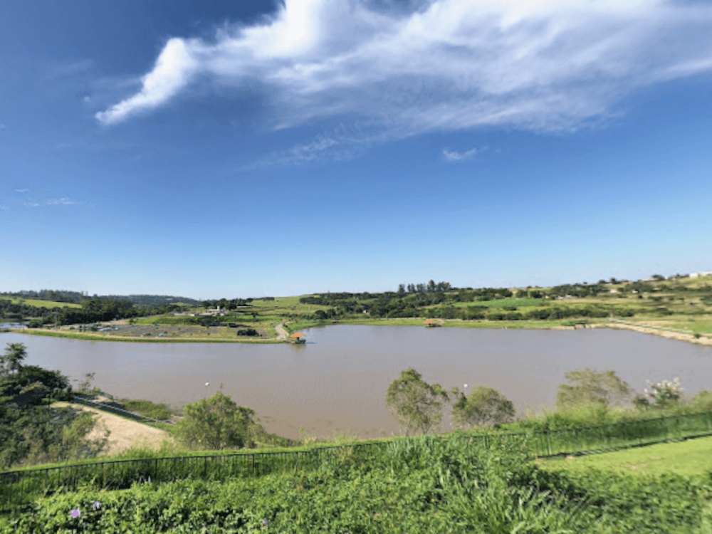 Vista panorâmica de um lago cercado por áreas verdes e céu aberto, representando um dos espaços de lazer ao ar livre em Indaiatuba.