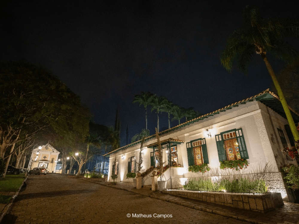 Construções históricas iluminadas à noite no Bairro Helvetia em Indaiatuba, cercadas por árvores e jardins