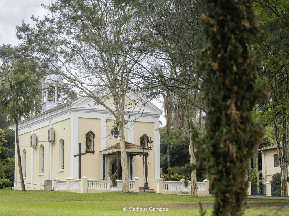 Igreja histórica cercada por árvores e jardins no Bairro Helvetia em Indaiatuba, destacando a arquitetura tradicional